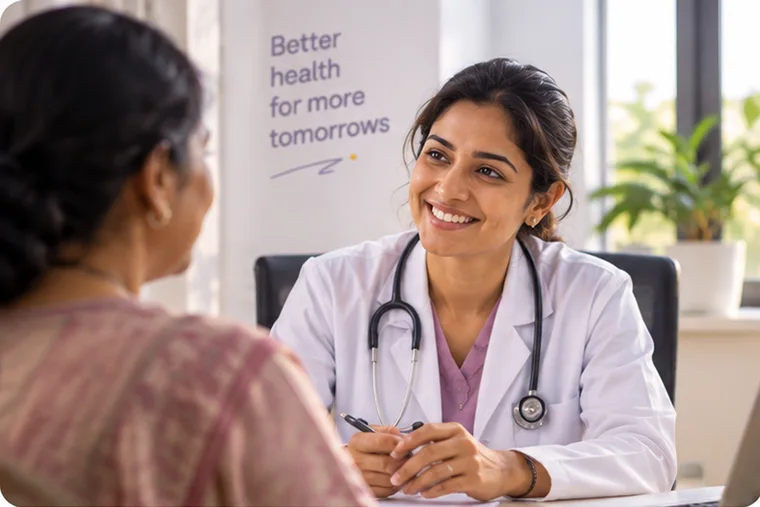 A doctor in conversation with a patient across a consulting-room desk, in daylight.